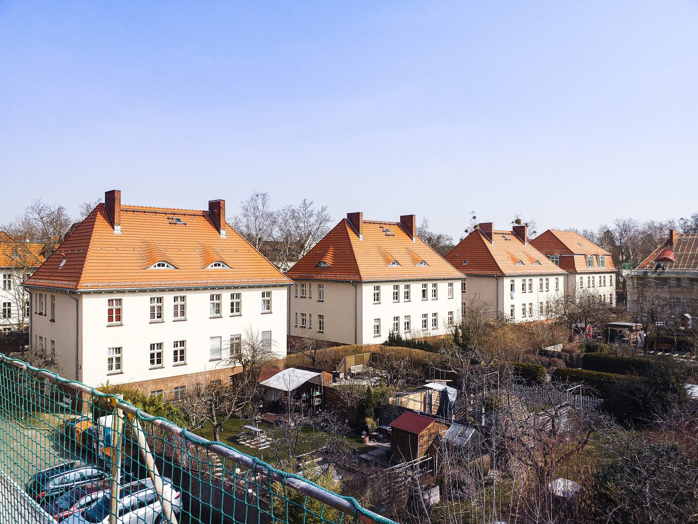 Reihe von Mehrfamilienhäusern mit roten Walmdächern in einer Berliner Siedlung