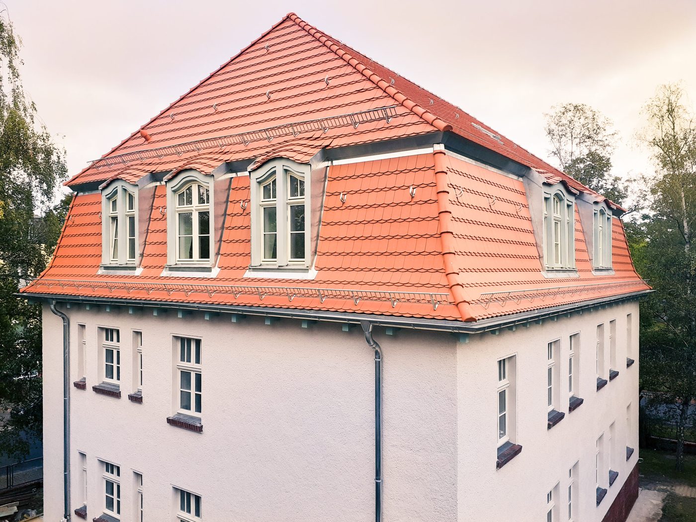 Sanierter Altbau mit neuem Mansarddach aus roten Ziegeln und Gauben